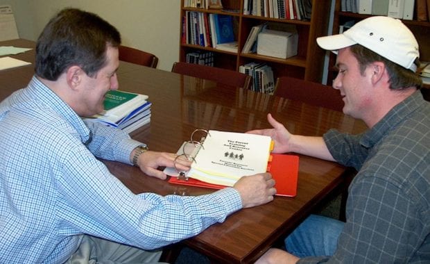 two men at a table looking at a document